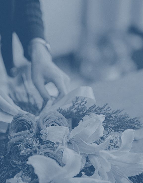 Manos de una florista preparando un ramo en su tienda